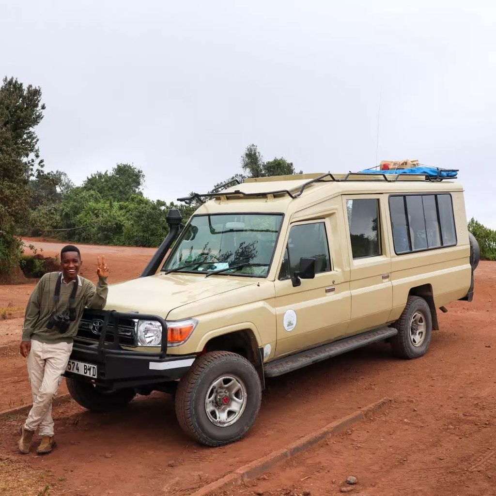 Edgar Laizer beside a safari vehicle in Tanzania